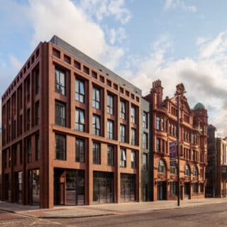 Apartment interior with modern decor, soft lighting, a comfortable grey sofa, a round wooden coffee table, abstract wall art, a flat-screen TV, and a sleek kitchen counter.