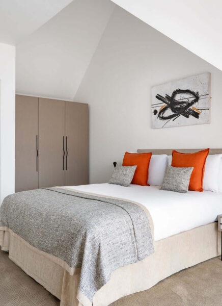 Modern luxury apartment with sleek kitchen, contemporary furnishings, and large windows showcasing city skyline views. Neutral tones paired with wooden accents create a welcoming, elegant ambiance.
