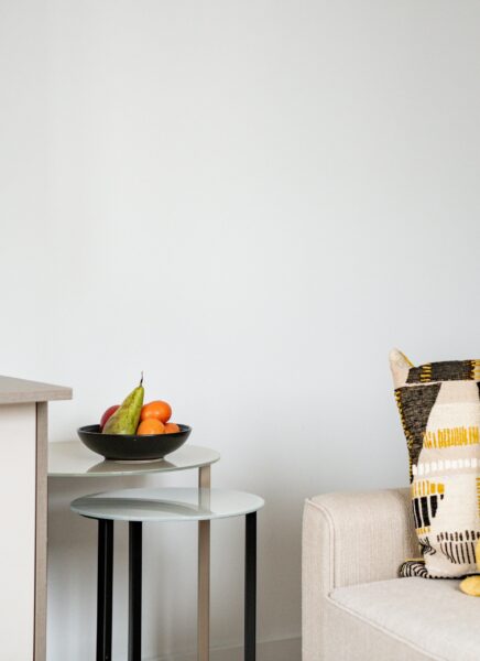 Cozy living room with a modern design, featuring a plush gray sofa, wooden coffee table, large windows with sheer curtains, and a stylish beige area rug.