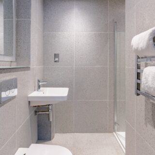 A modern hotel lobby with large windows, plush seating, and sleek decor. Natural light illuminates the space, creating a welcoming and sophisticated atmosphere.