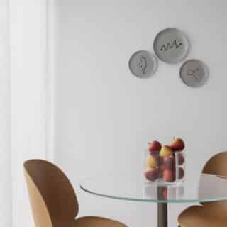 A modern living room with a large window, city view, comfortable sofa, stylish wooden furniture, a round coffee table, plants, and decorative items creating a cozy atmosphere.