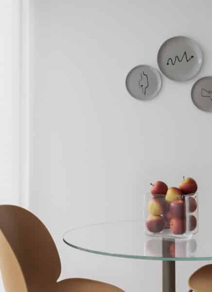 A modern living room with a large window, city view, comfortable sofa, stylish wooden furniture, a round coffee table, plants, and decorative items creating a cozy atmosphere.