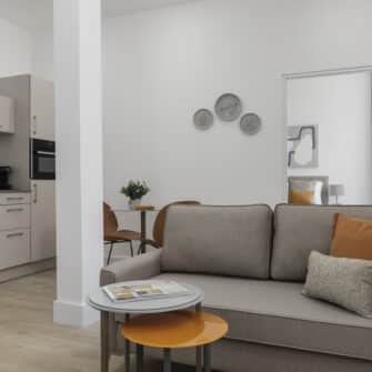 A modern living room featuring vibrant blue sofas, a cozy fireplace, elegant artwork, and large windows allowing natural light to fill the space.