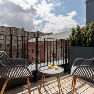 An elegantly furnished modern studio apartment featuring a cozy bed, stylish seating area, well-equipped kitchenette, and large windows with ample natural light, creating a warm and inviting atmosphere.