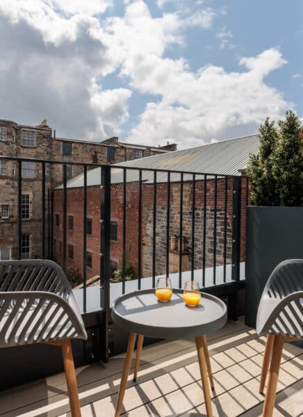 An elegantly furnished modern studio apartment featuring a cozy bed, stylish seating area, well-equipped kitchenette, and large windows with ample natural light, creating a warm and inviting atmosphere.