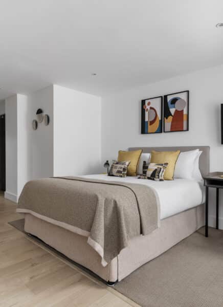 A modern apartment interior featuring a cozy living area with a large sofa, stylish furniture, elegant decor, and expansive glass windows offering a cityscape view.