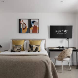 A modern living room with gray sofa, yellow armchair, minimalist wooden coffee table, abstract artwork on the wall, and large windows with sheer curtains.