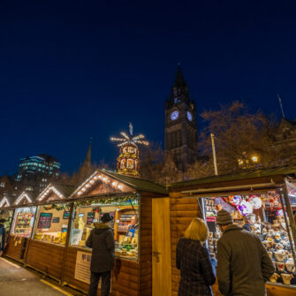A contemporary, well-furnished open-plan living area with a kitchen, dining table, lounging space, and large windows offering ample natural light. Decor includes modern art and sleek furniture.