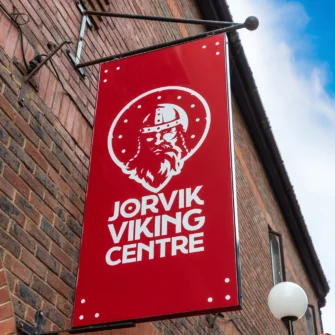 Jorvik Viking Centre exterior with a sign, large glass windows, and people walking outside under a cloudy sky.