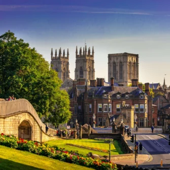 A magnificent view of the York Minster, showcasing its intricate Gothic architecture, towering spires, and detailed stained-glass windows under a clear blue sky.